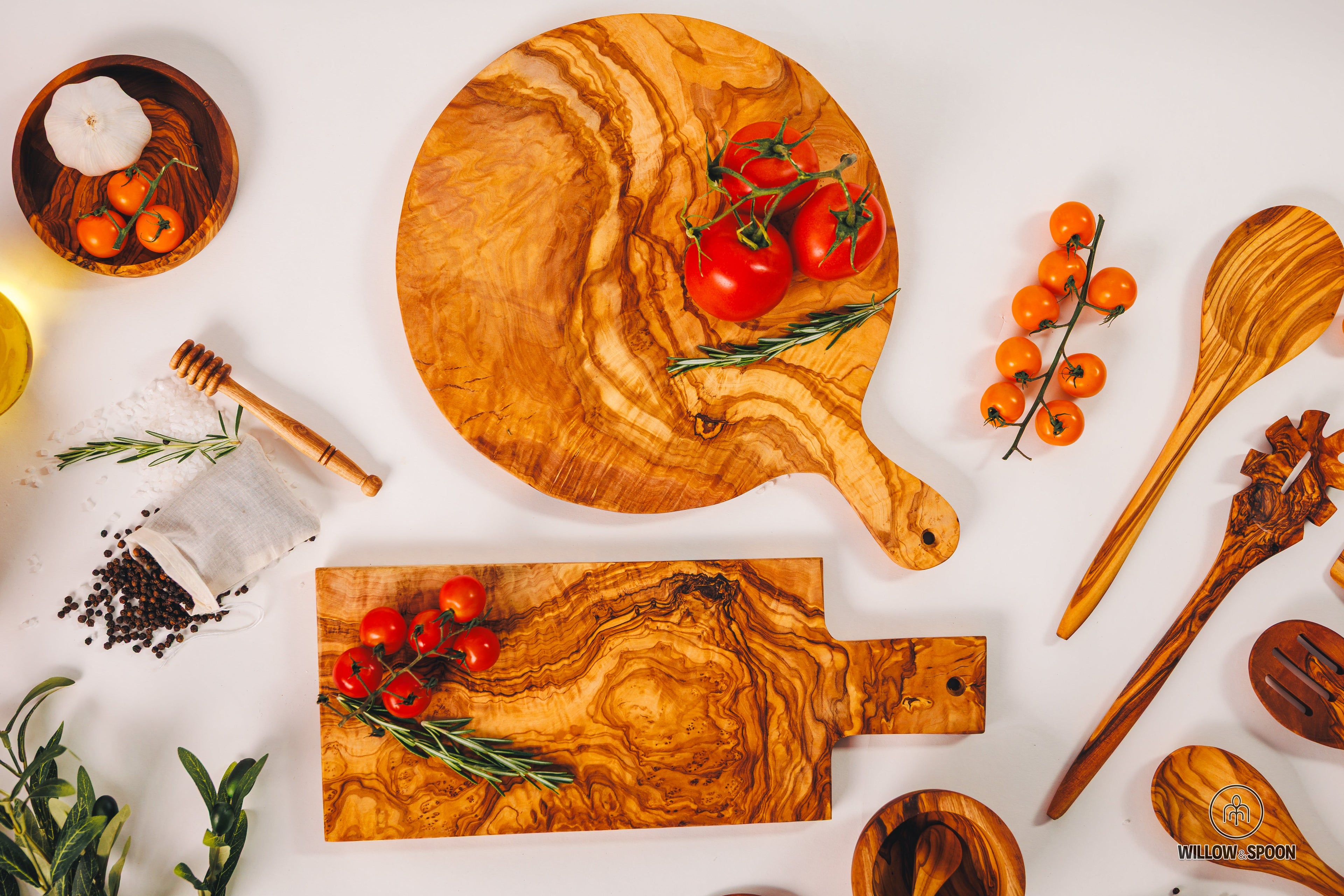 A variety of Willow & Spoon olive wood cutting boards and serving paddles showcasing natural live edges.