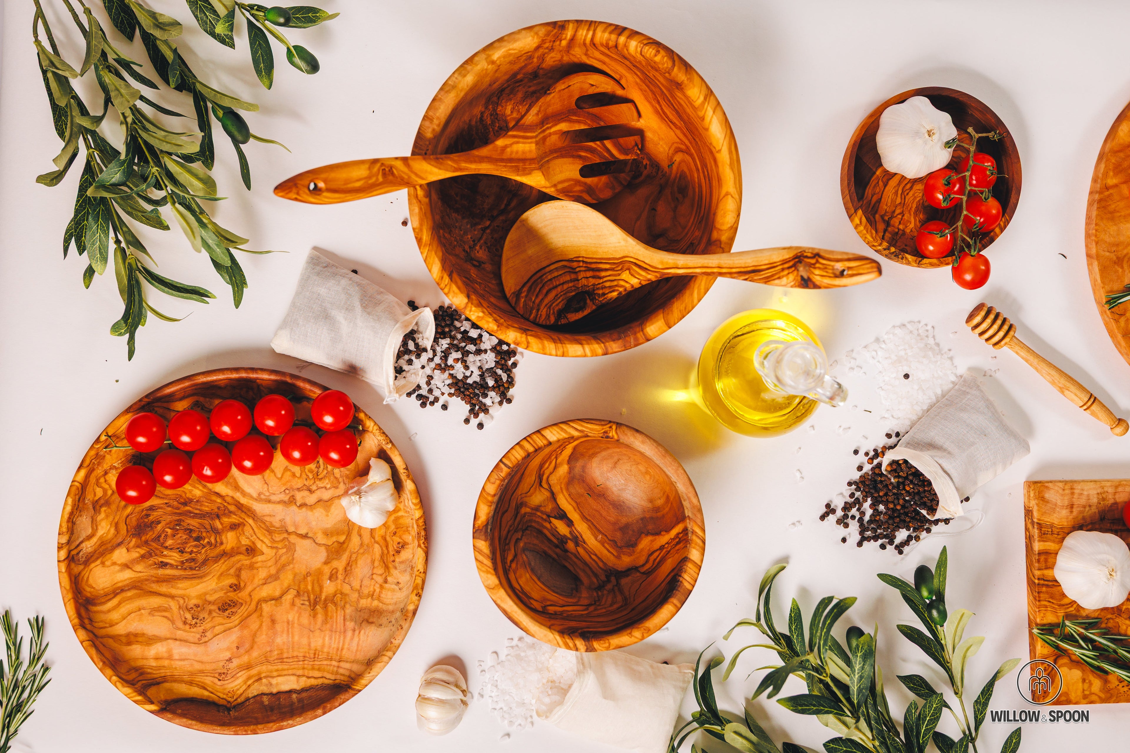 Artisan olive wood serverware collection featuring large salad bowls and matching serving spoons.