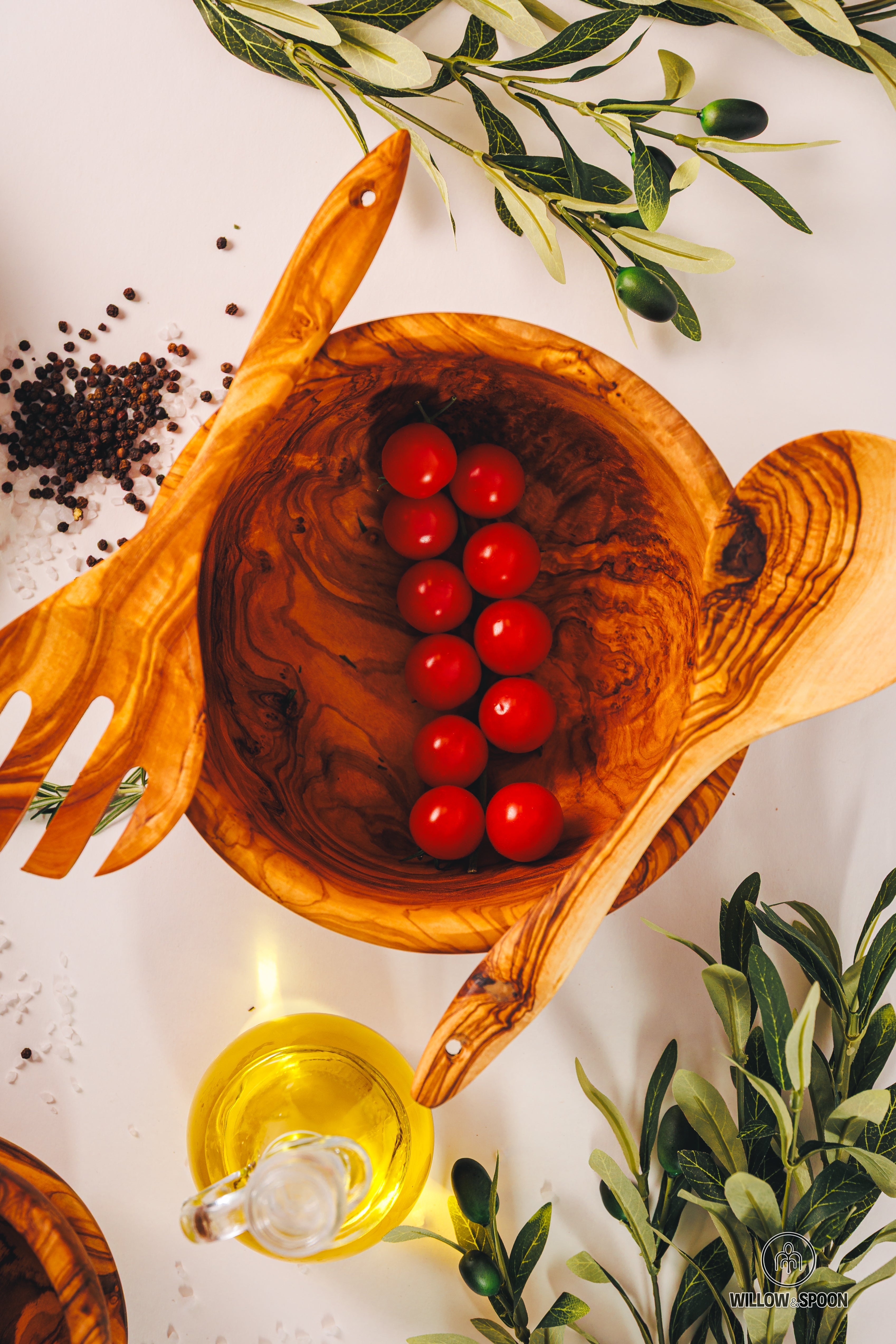 A top-down view of Willow & Spoon's best-selling olive wood salad bowl and server set, styled with fresh tomatoes and olive oil for a premium kitchen aesthetic.