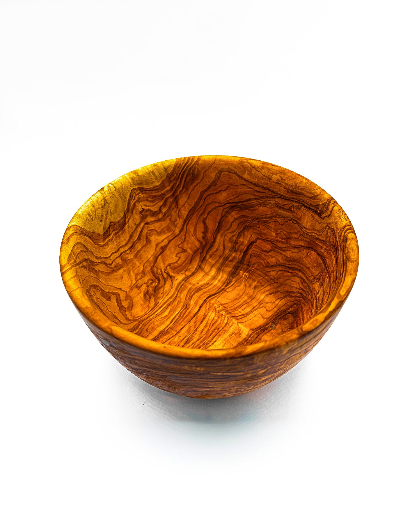 A perspective view of an artisan olive wood bowl, ideal for serving salads or used as a decorative fruit bowl on a kitchen island.