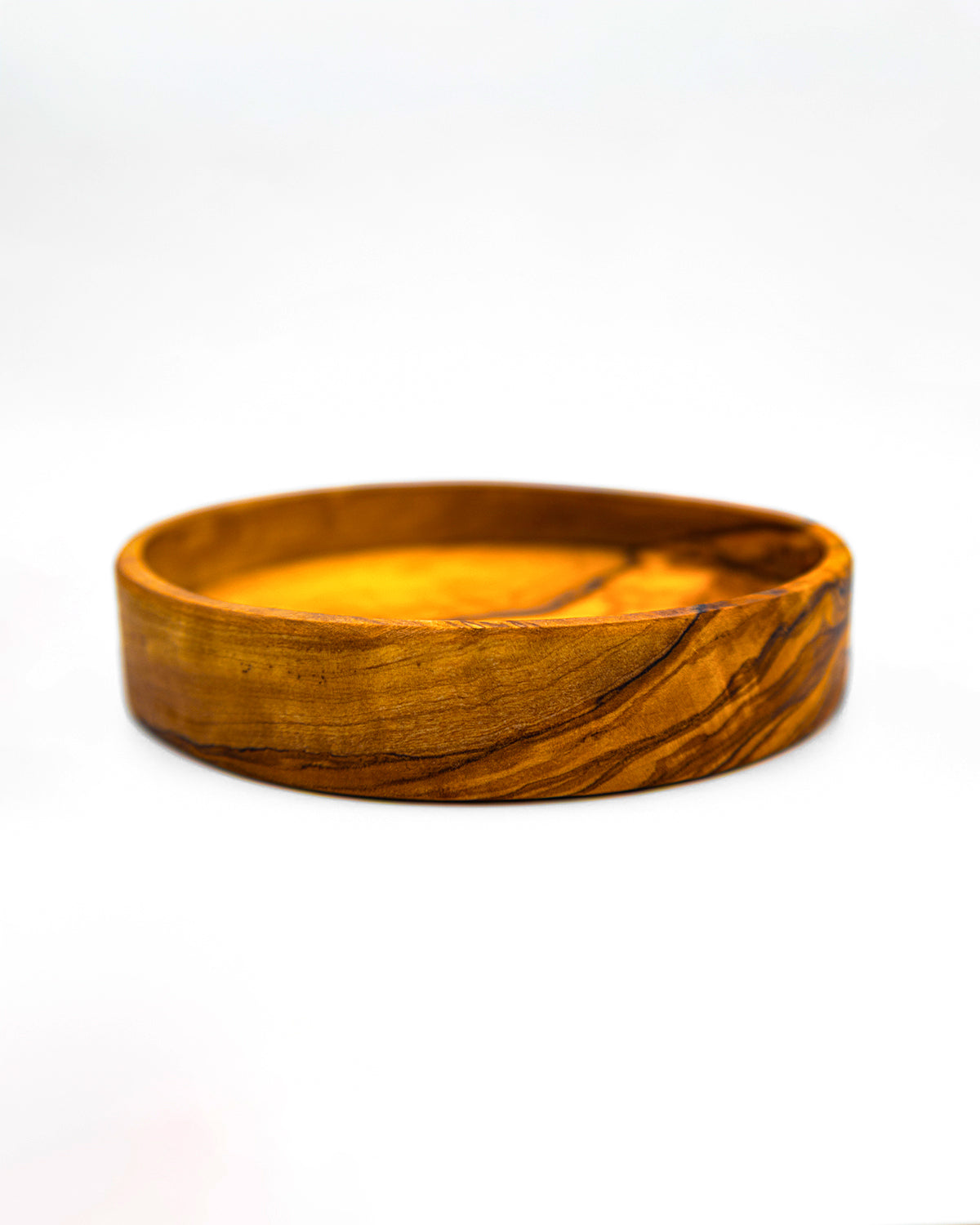 Side view of an artisan olive wood trinket bowl showing the smooth carved edges and sturdy base.