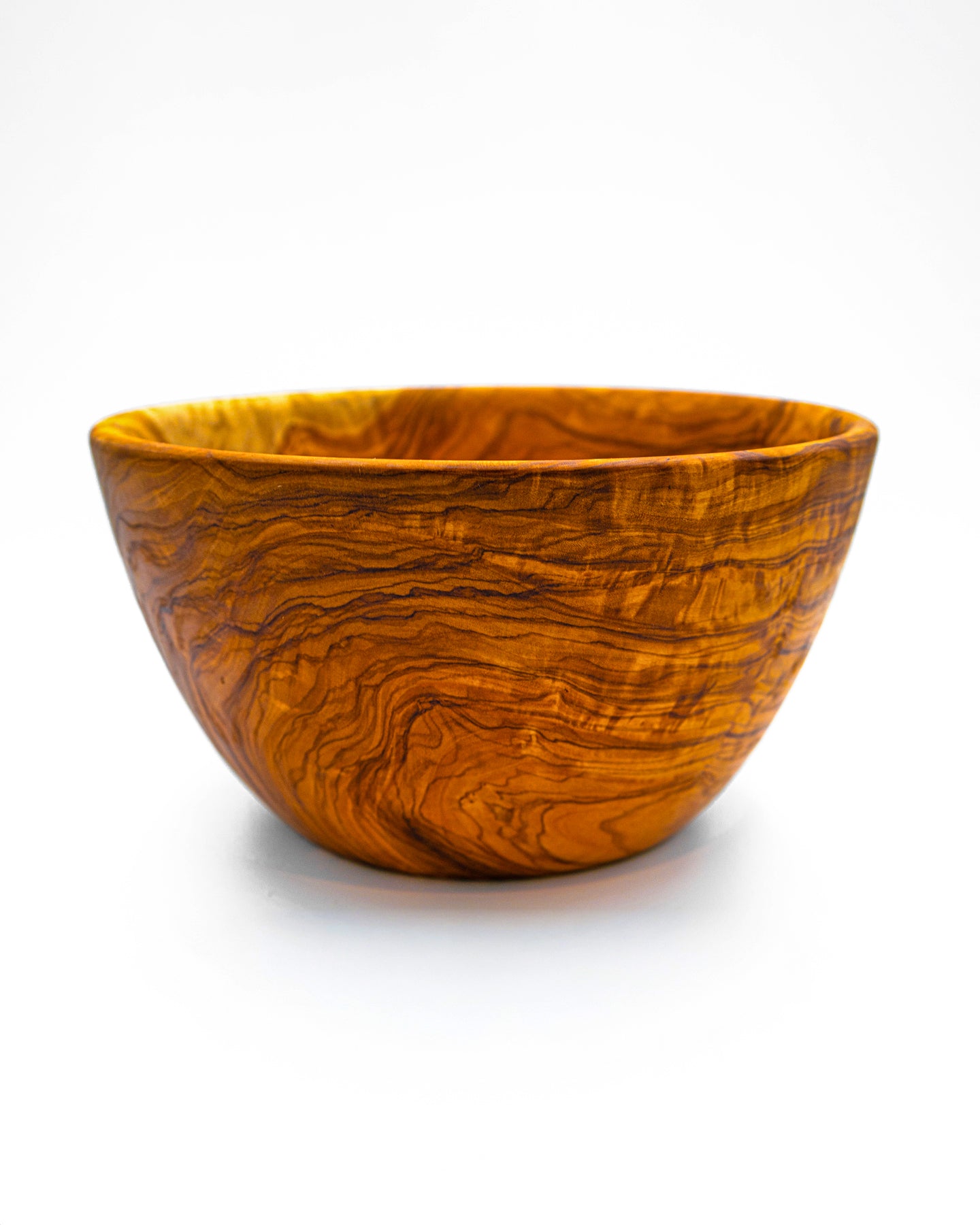Side profile of a hand-carved olive wood centerpiece bowl highlighting its deep vessel design and sturdy, rustic aesthetic.
