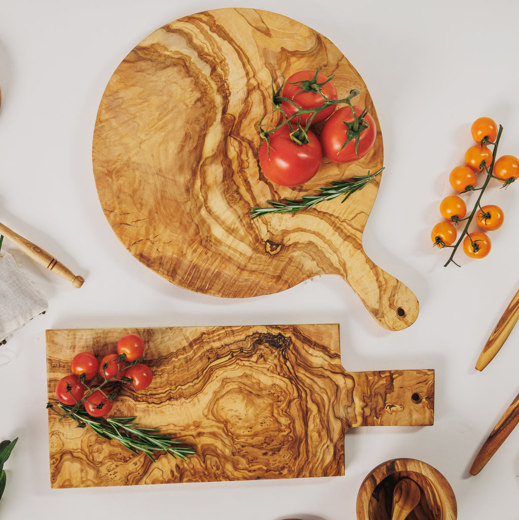 Olive wood cutting board set with round and rectangular boards, styled with cherry tomatoes and rosemary on a white surface