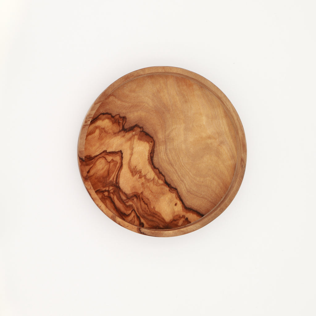  Overhead view of a handcrafted Tunisian olive wood dipping dish showing the natural grain on a white background.