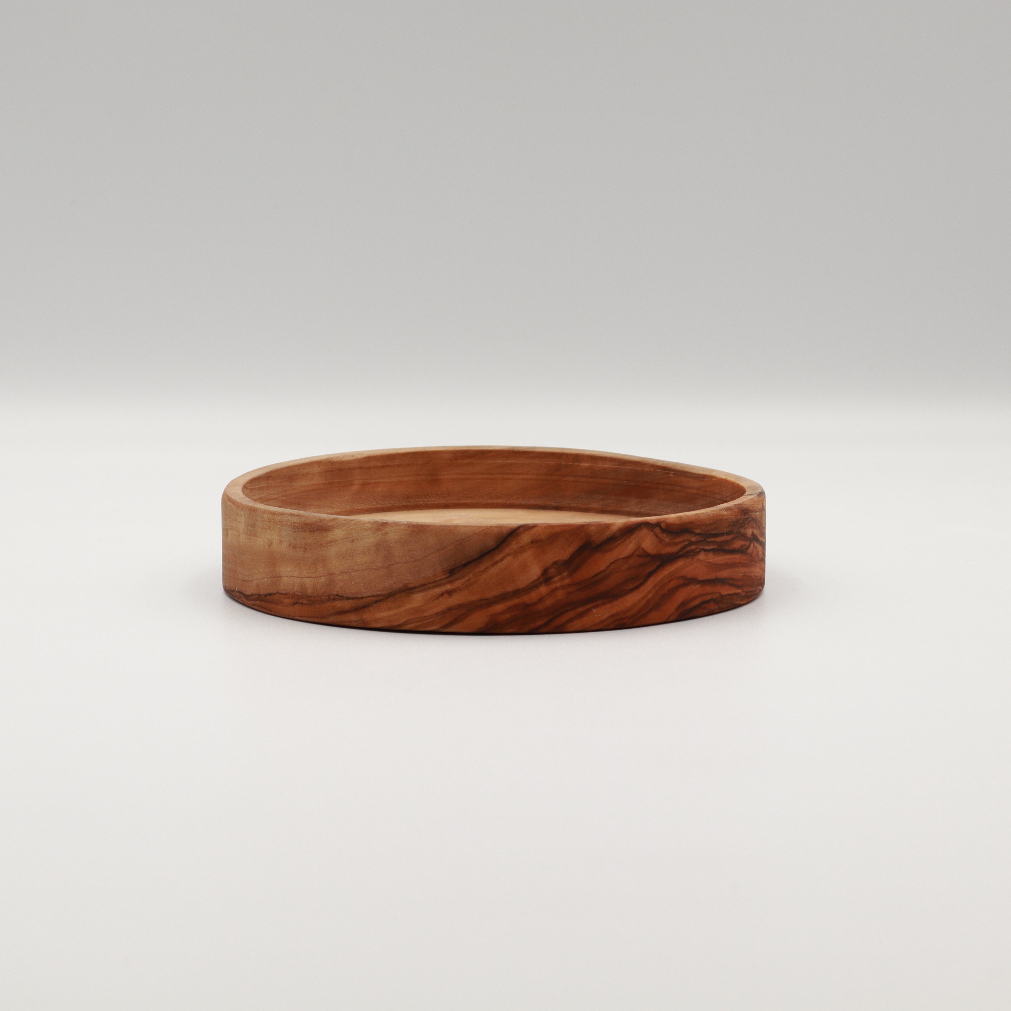 Handcrafted Tunisian olive wood dipping dish with a shallow profile, shown on a white background highlighting the natural grain.