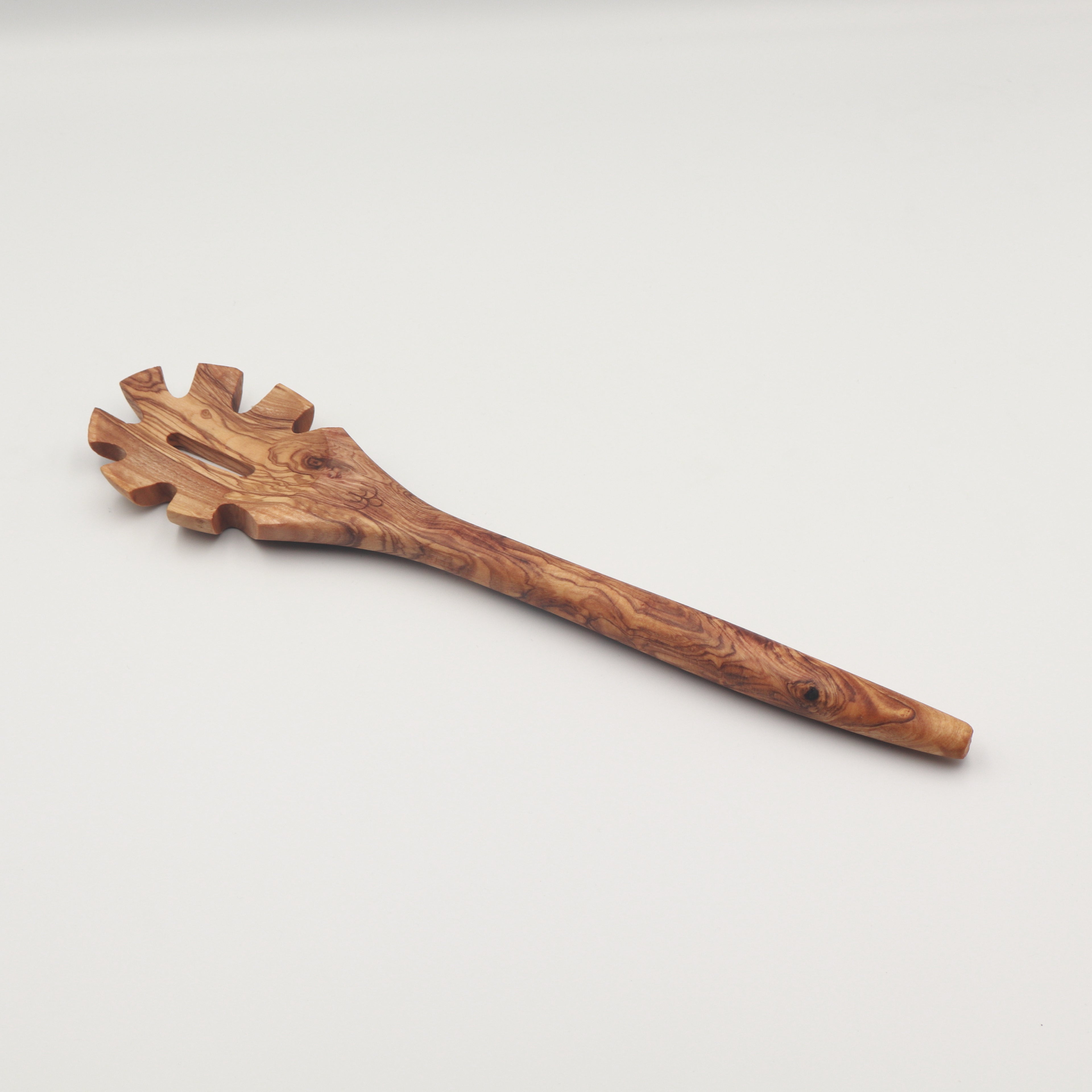 Handcrafted Tunisian olive wood pasta server with a toothed head, shown on a white background highlighting the natural grain.