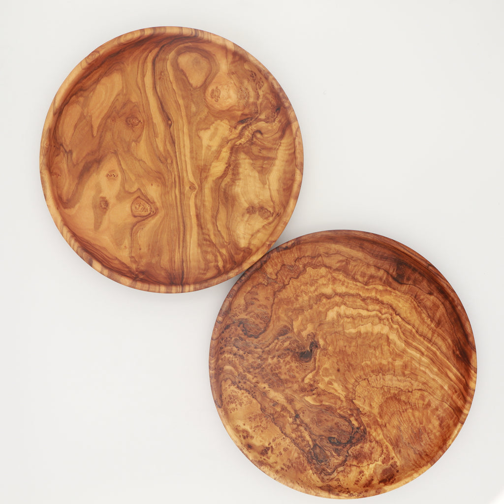 Pair of handcrafted Tunisian olive wood round plates showing distinctive grain patterns on a white background.