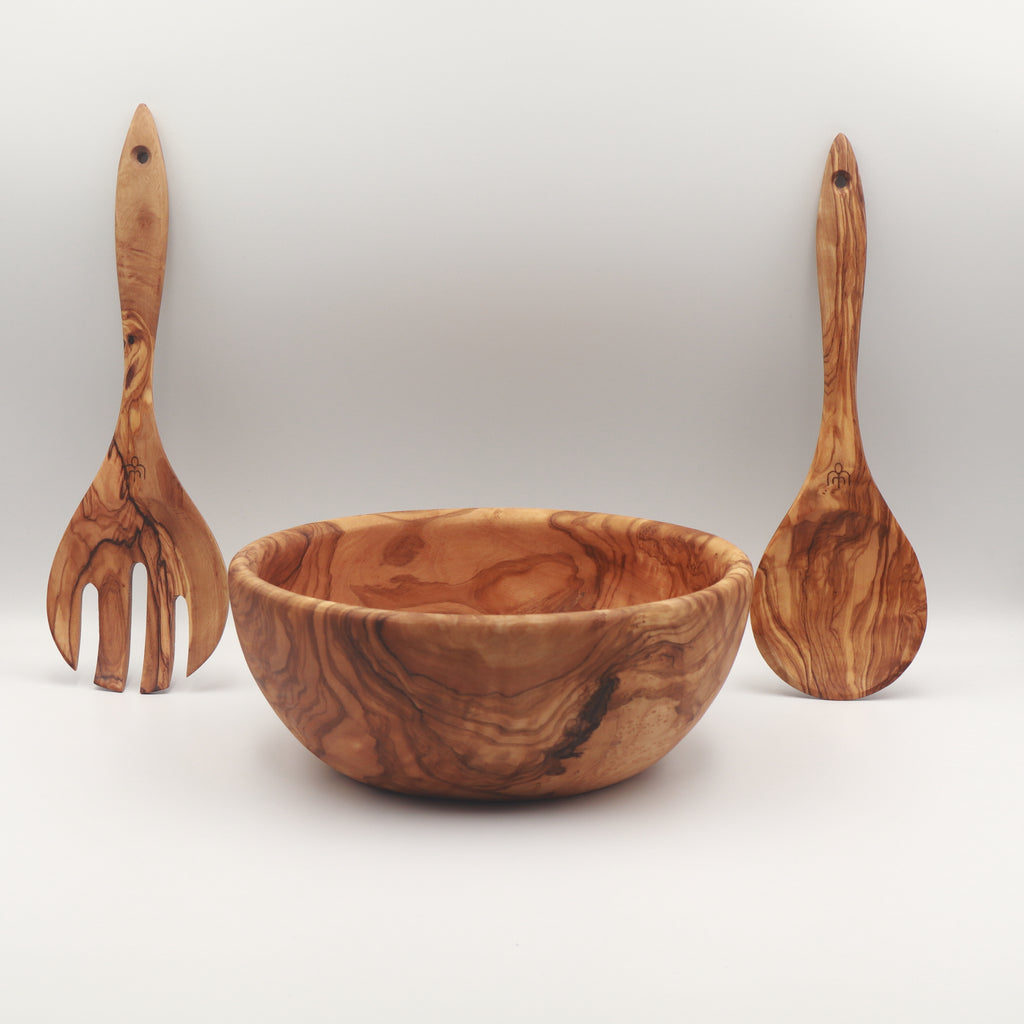 Handcrafted Tunisian olive wood salad bowl with two salad servers standing upright on either side on a white background.