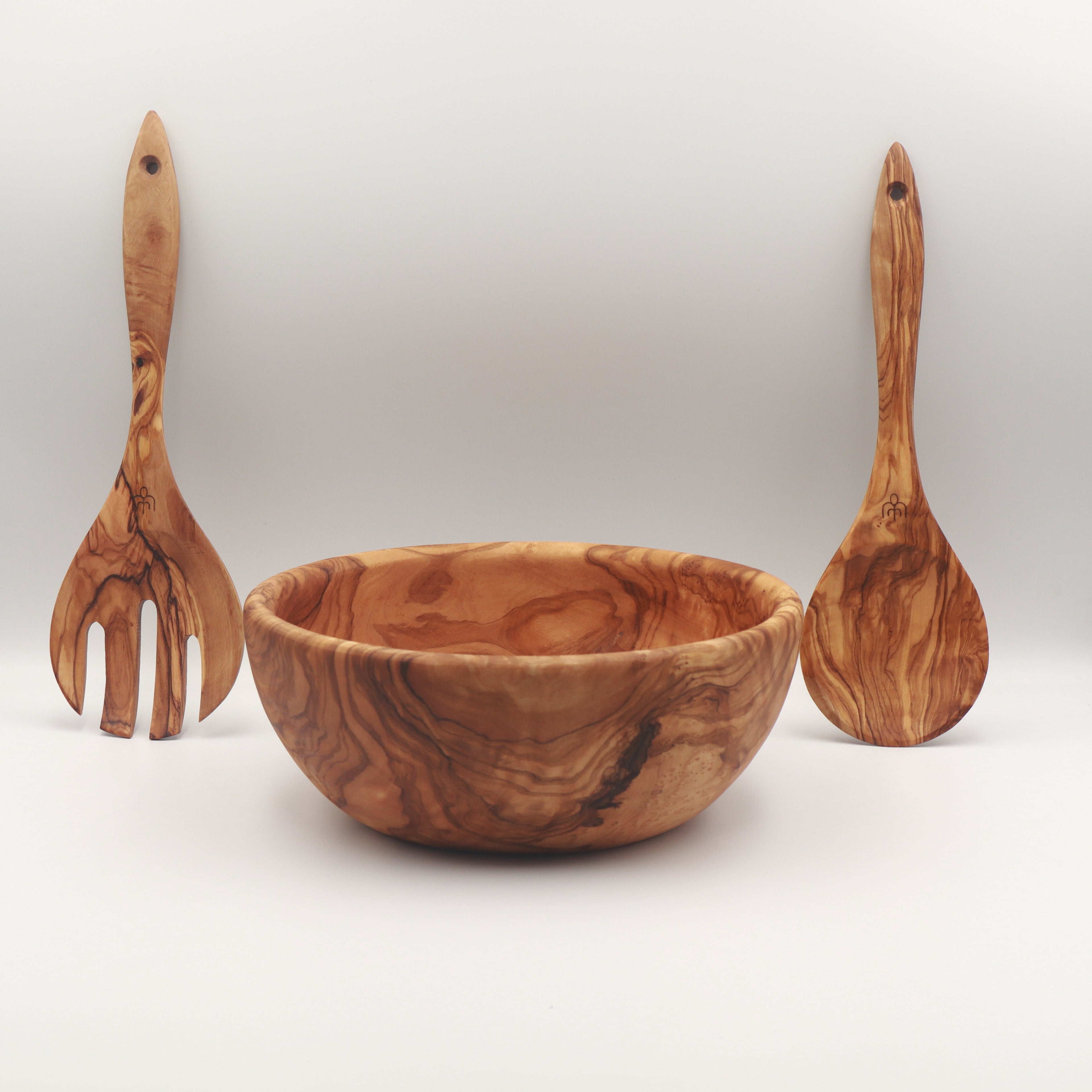 Handcrafted Tunisian olive wood salad bowl with two salad servers standing upright on either side on a white background.