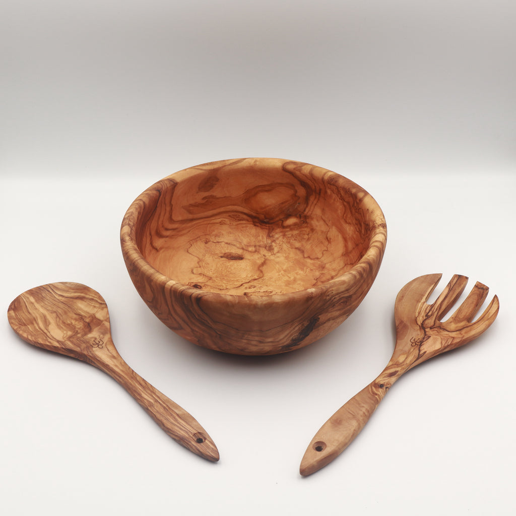 Handcrafted Tunisian olive wood salad bowl with two matching salad servers laid alongside on a white background.