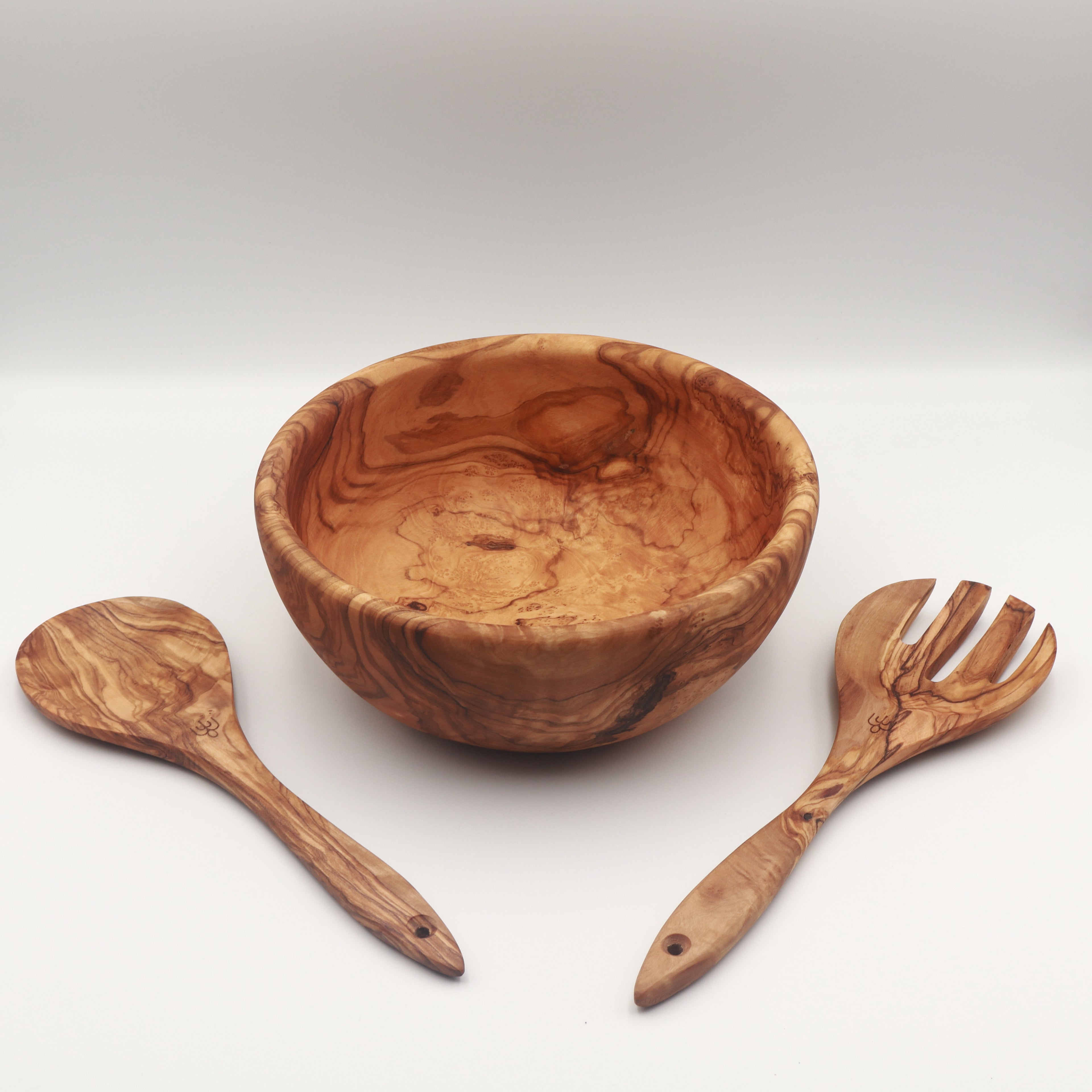 Handcrafted Tunisian olive wood salad bowl with two matching salad servers laid alongside on a white background.