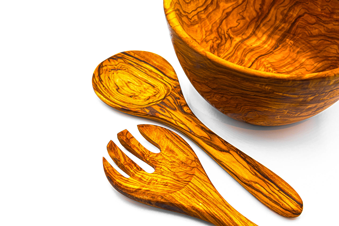Close-up detail of olive wood salad servers resting next to a wooden bowl, showing the smooth finish and rich wood texture.