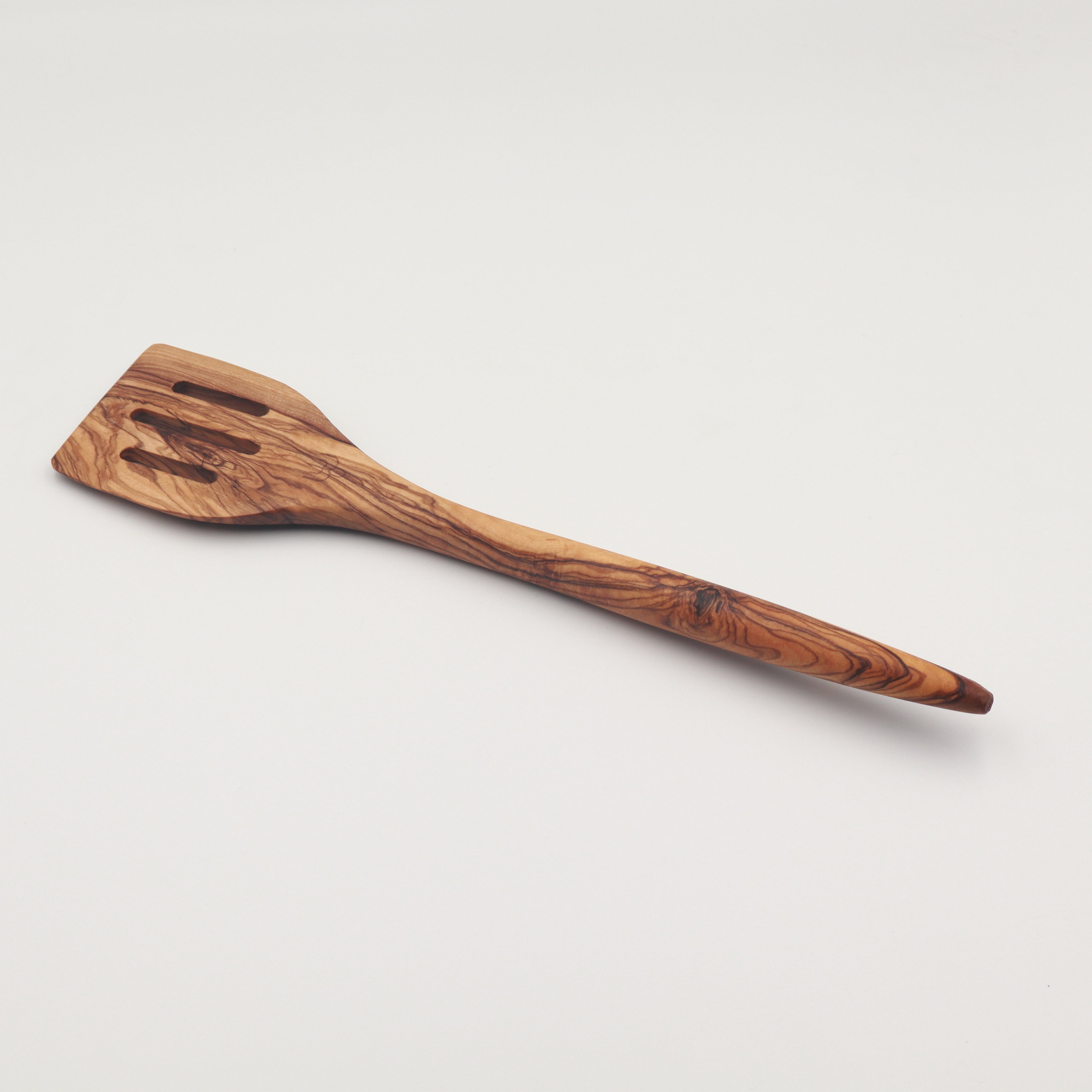 Handcrafted Tunisian olive wood slotted spatula shown on a white background highlighting the natural grain.