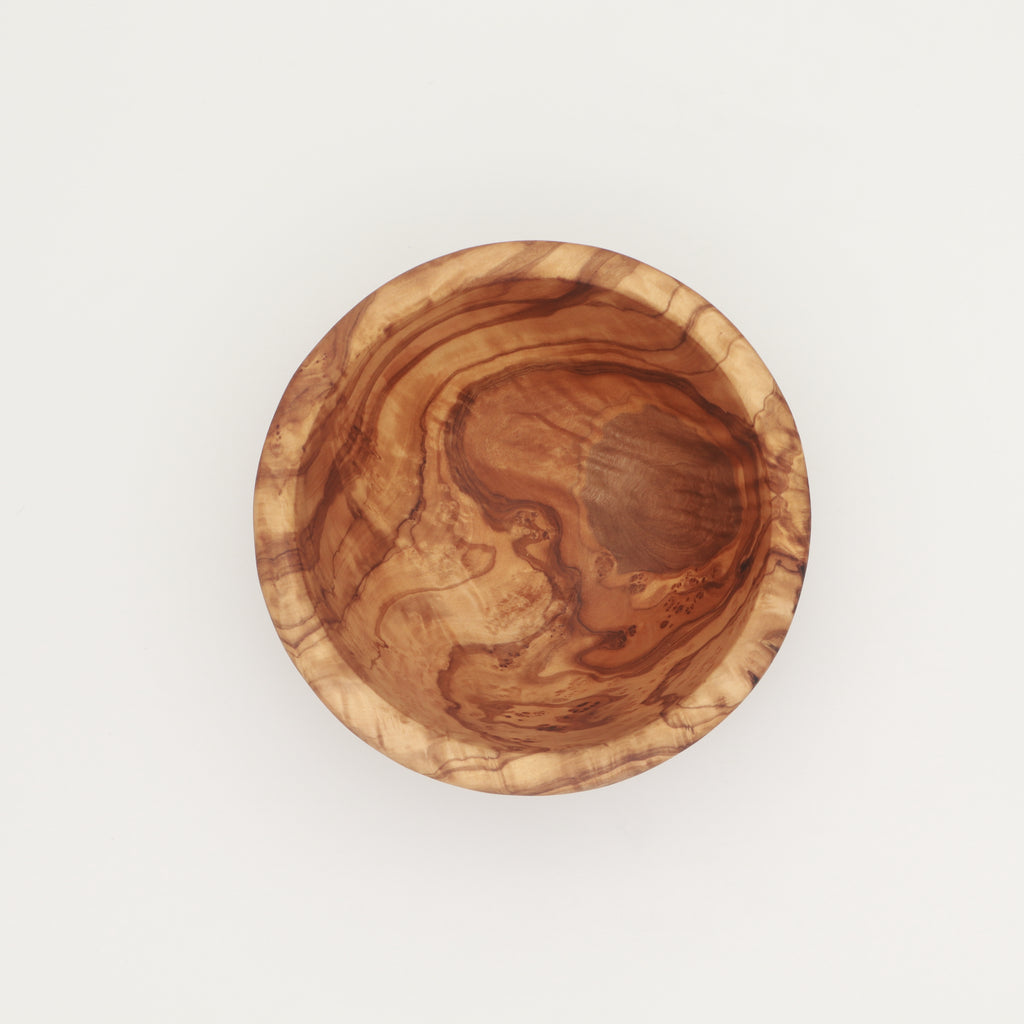 Overhead view of a single handcrafted Tunisian olive wood small bowl showing the interior grain on a white background.