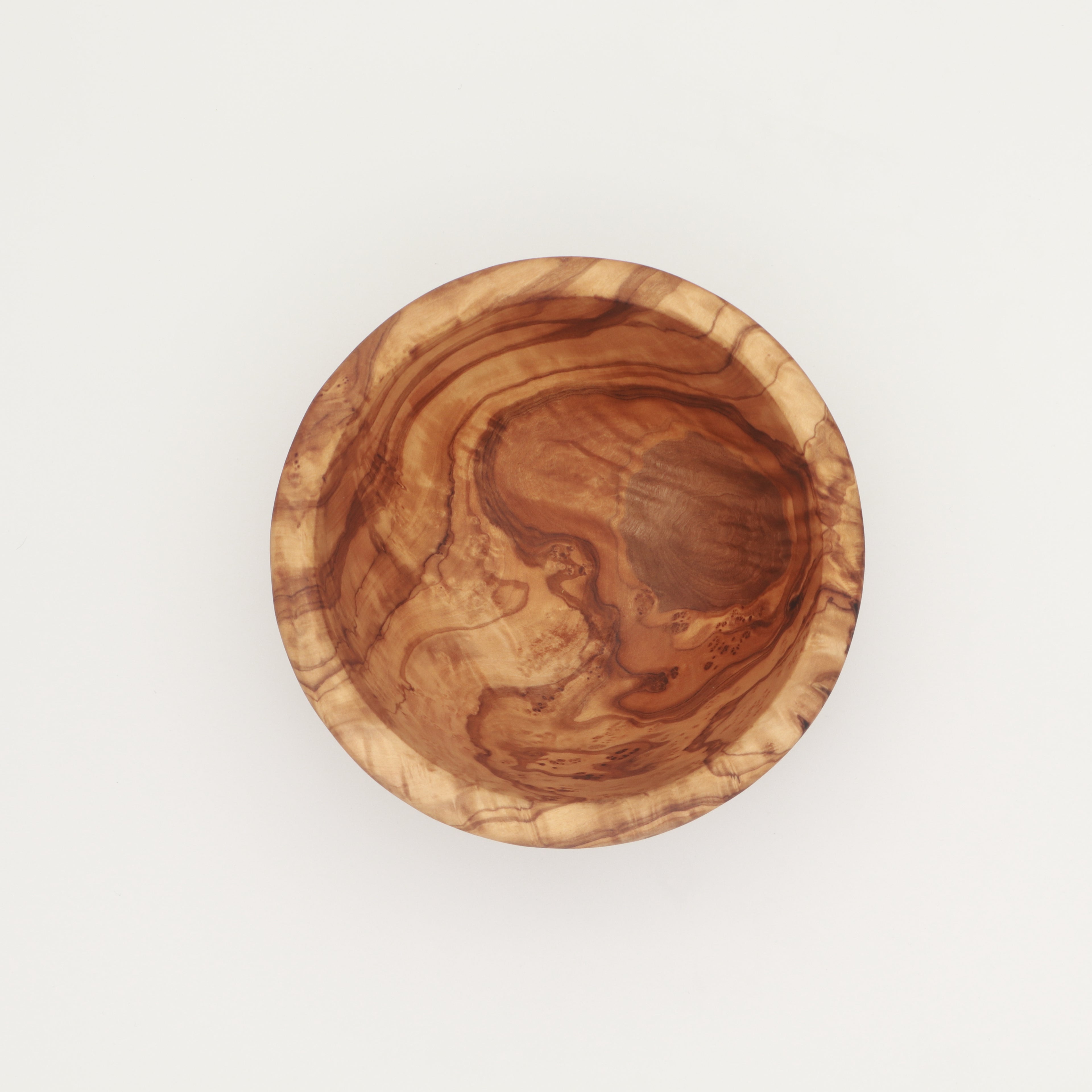 Overhead view of a single handcrafted Tunisian olive wood small bowl showing the interior grain on a white background.