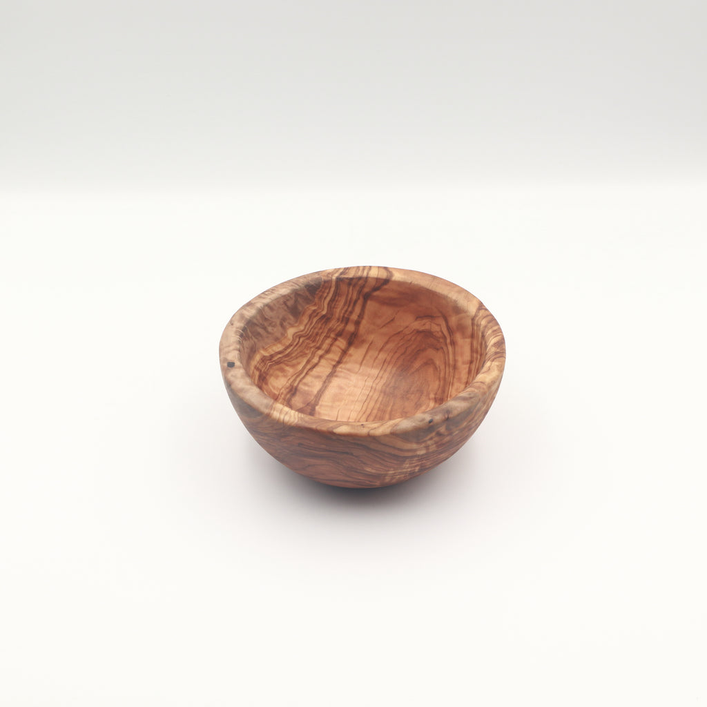 Three-quarter view of a single handcrafted Tunisian olive wood small bowl on a white background highlighting the natural grain.