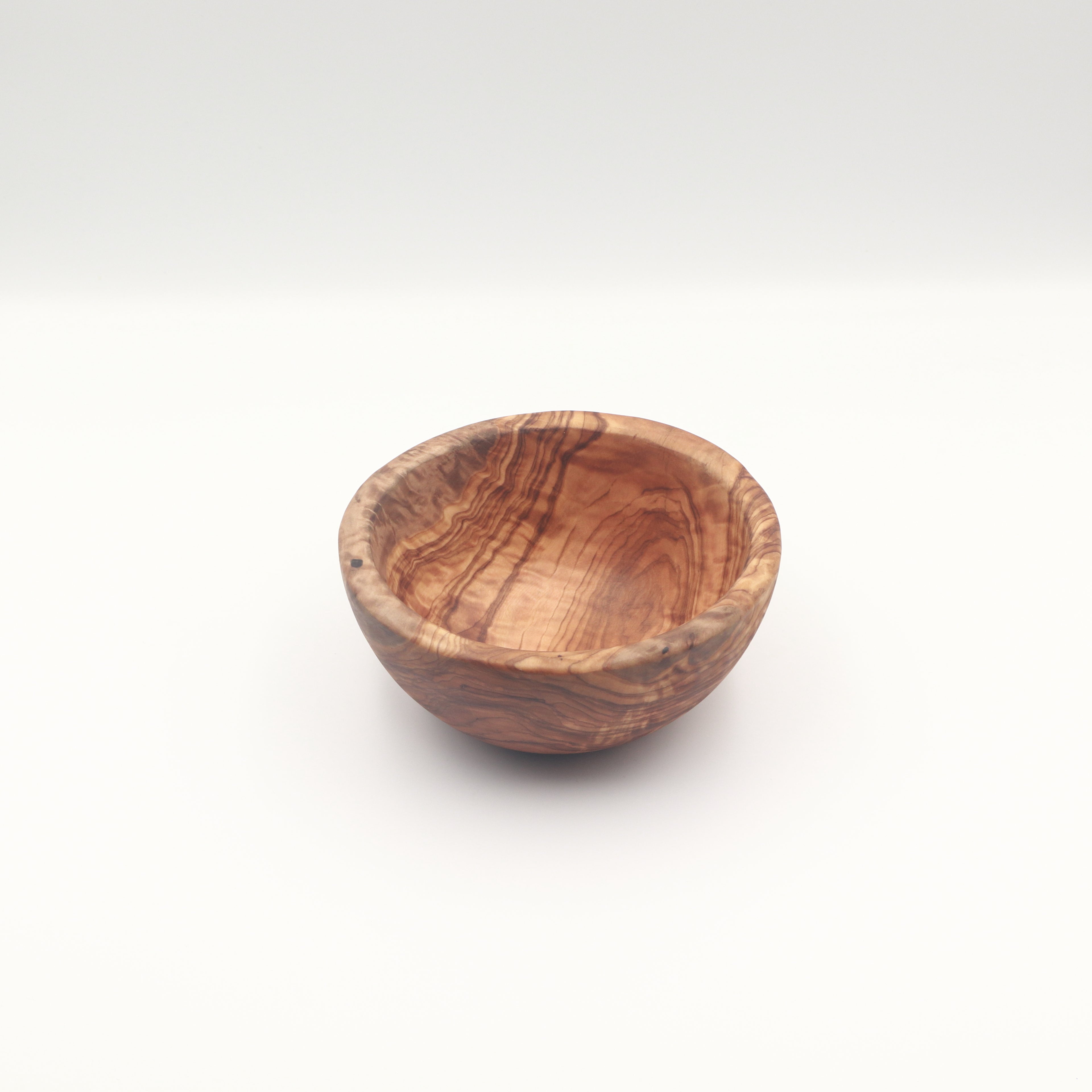 Three-quarter view of a single handcrafted Tunisian olive wood small bowl on a white background highlighting the natural grain.