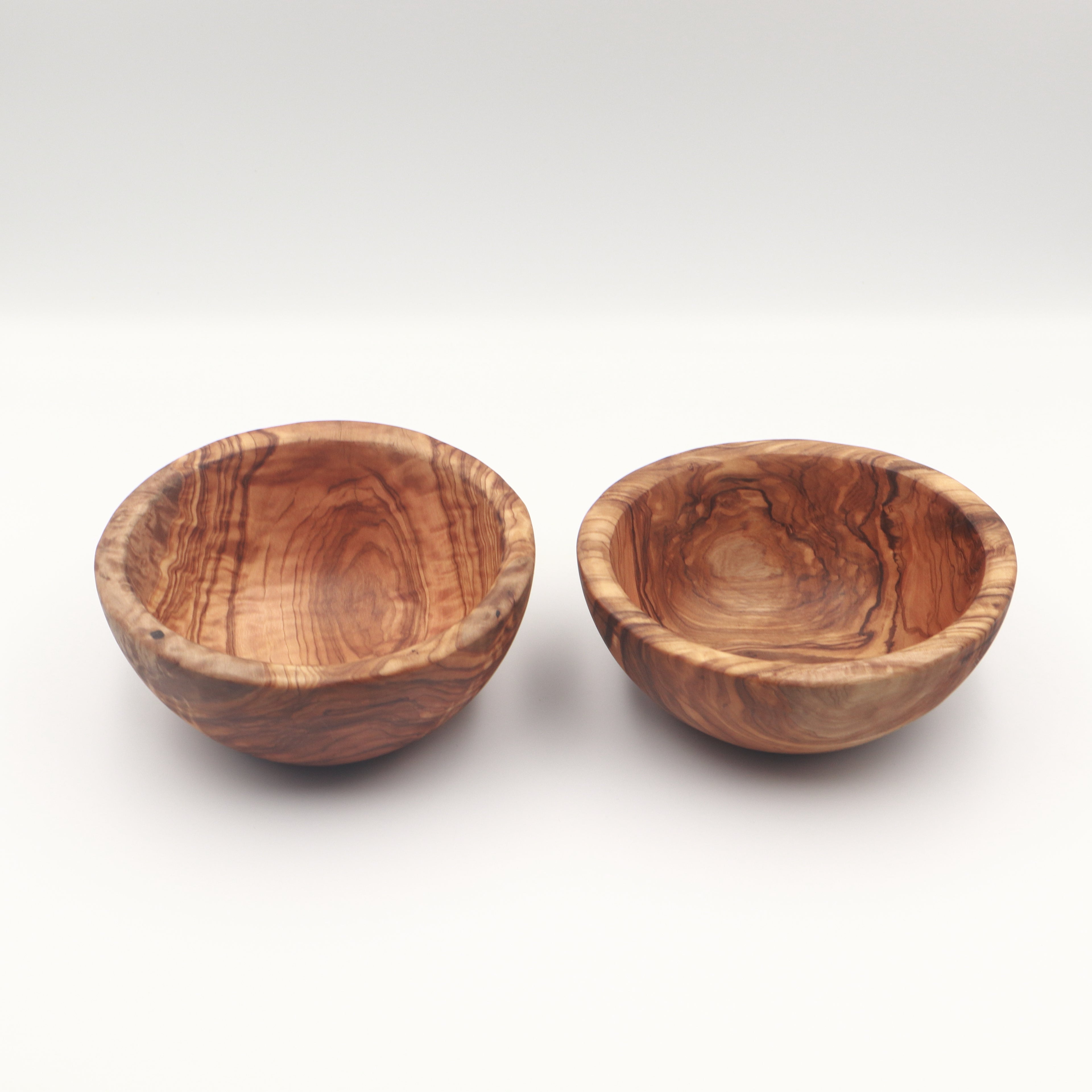Two handcrafted Tunisian olive wood small bowls side by side, shown on a white background highlighting the natural grain.