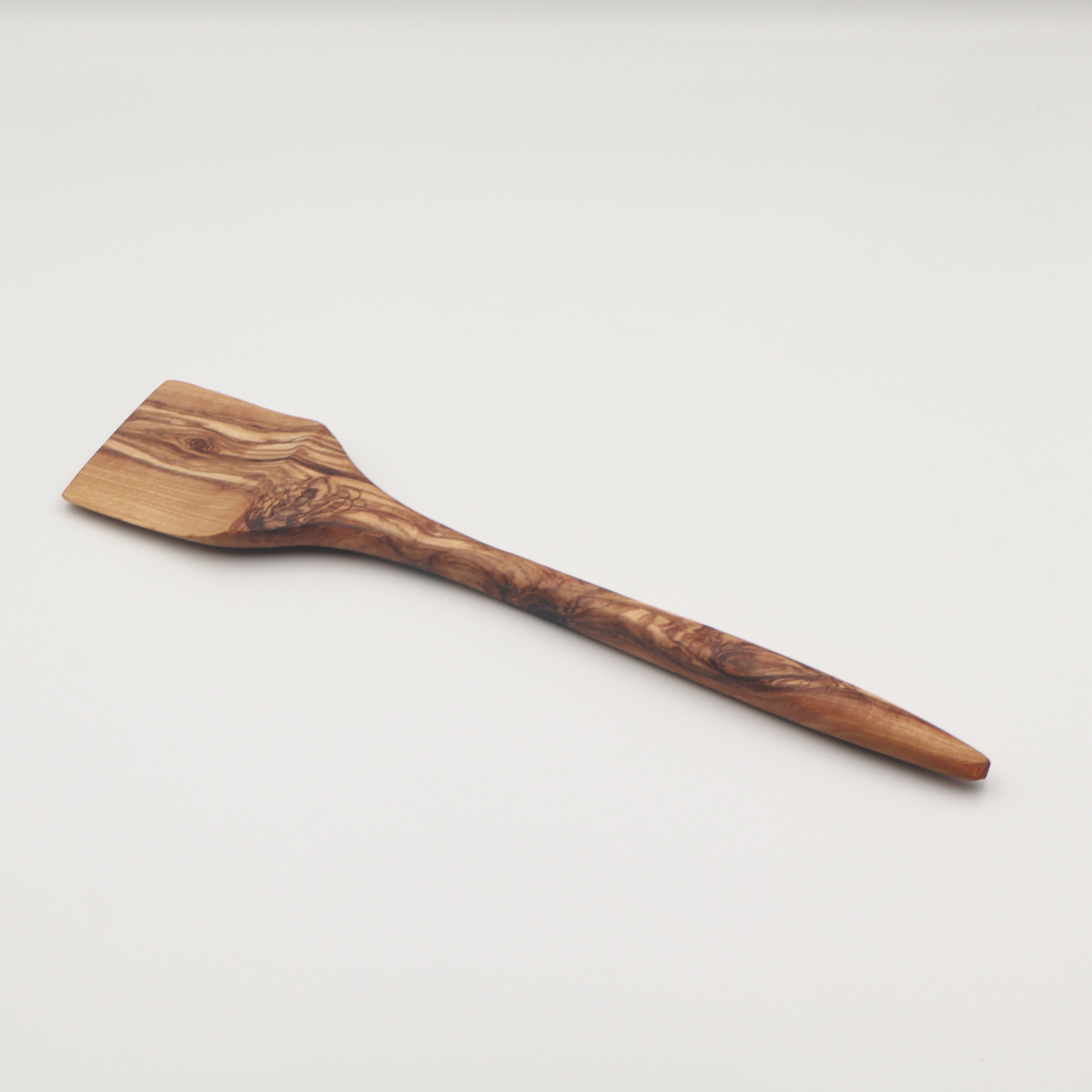 Handcrafted Tunisian olive wood spatula with a solid flat head, shown on a white background highlighting the natural grain.