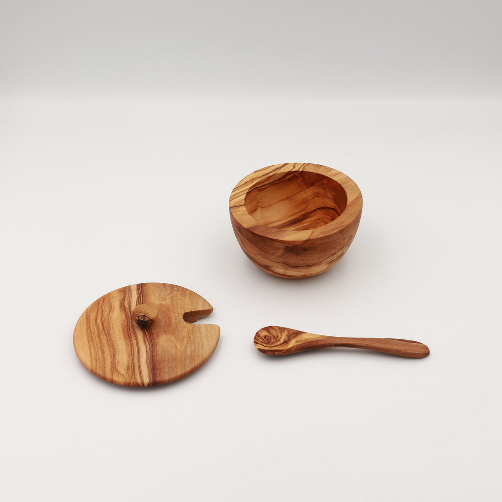 Angled view of a handcrafted Tunisian olive wood spice box shown disassembled with the open box, lid, and serving spoon on a white background.