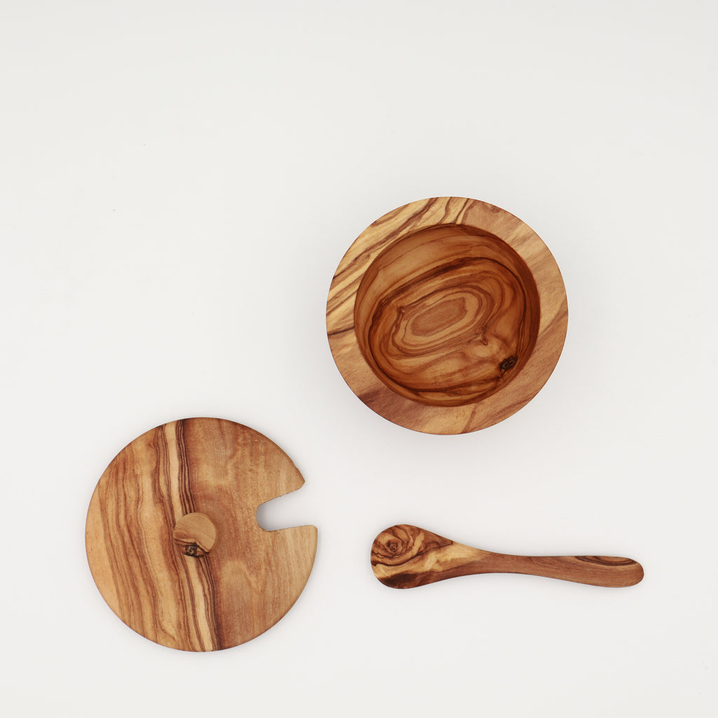 Overhead view of a handcrafted Tunisian olive wood spice box shown disassembled with the open box, lid, and serving spoon on a white background.