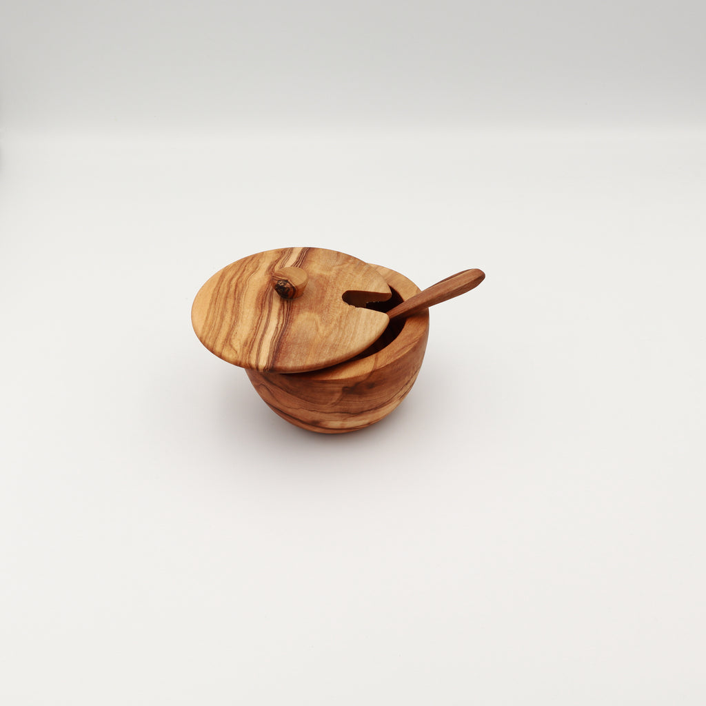 Handcrafted Tunisian olive wood spice box with the lid slightly ajar and a serving spoon through the slot, shown on a white background.