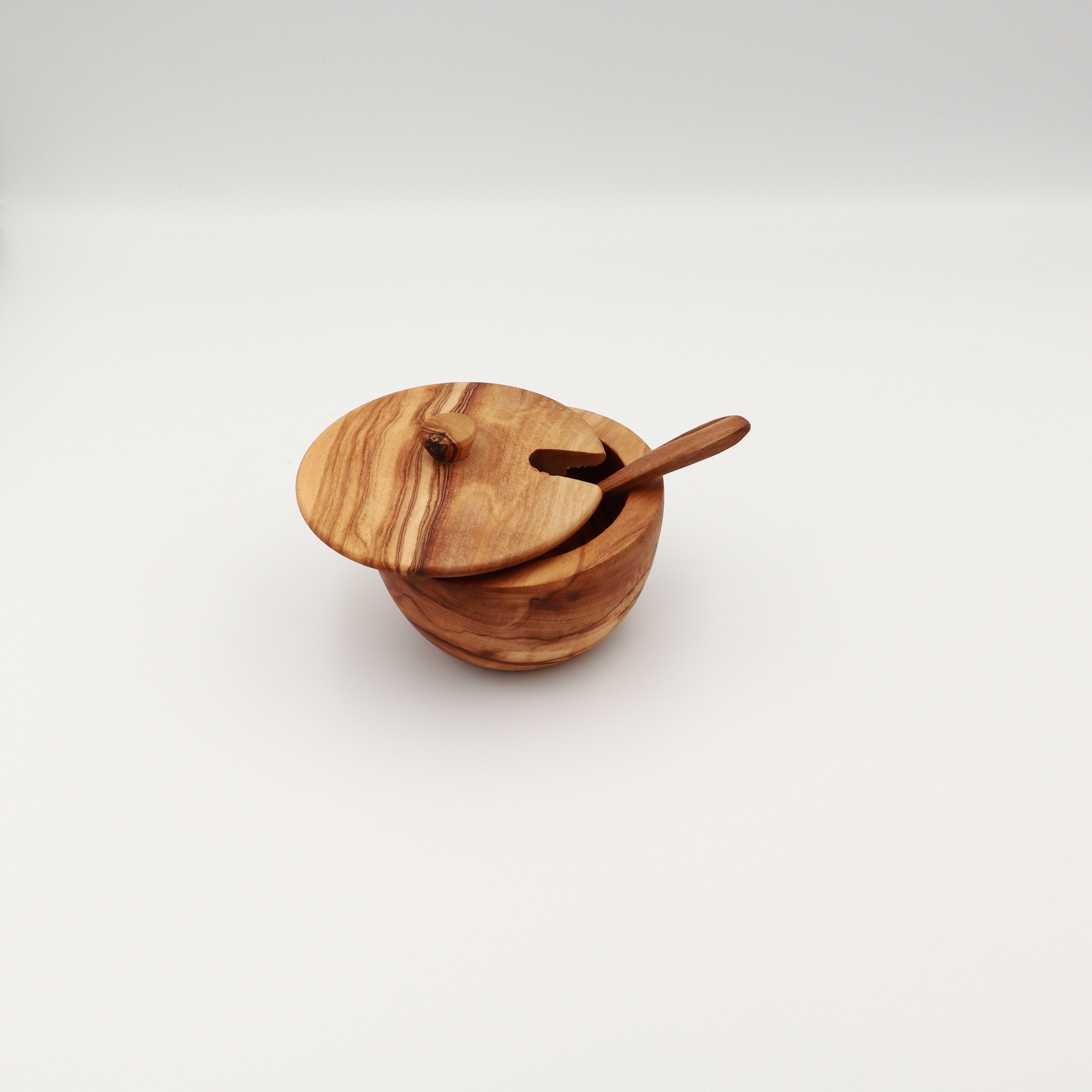 Handcrafted Tunisian olive wood spice box with the lid slightly ajar and a serving spoon through the slot, shown on a white background.
