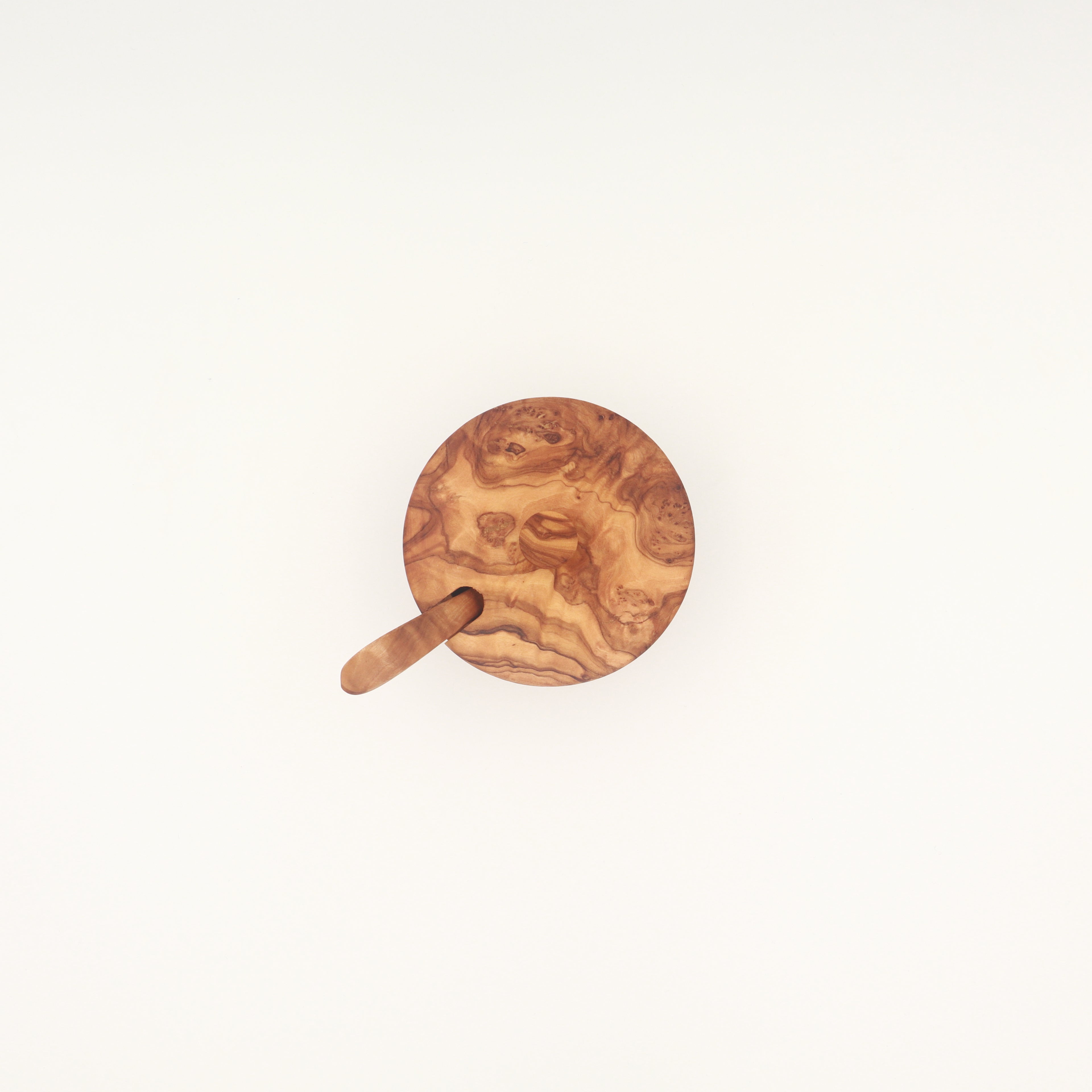 Overhead view of a handcrafted Tunisian olive wood spice box with lid and serving spoon on a white background.