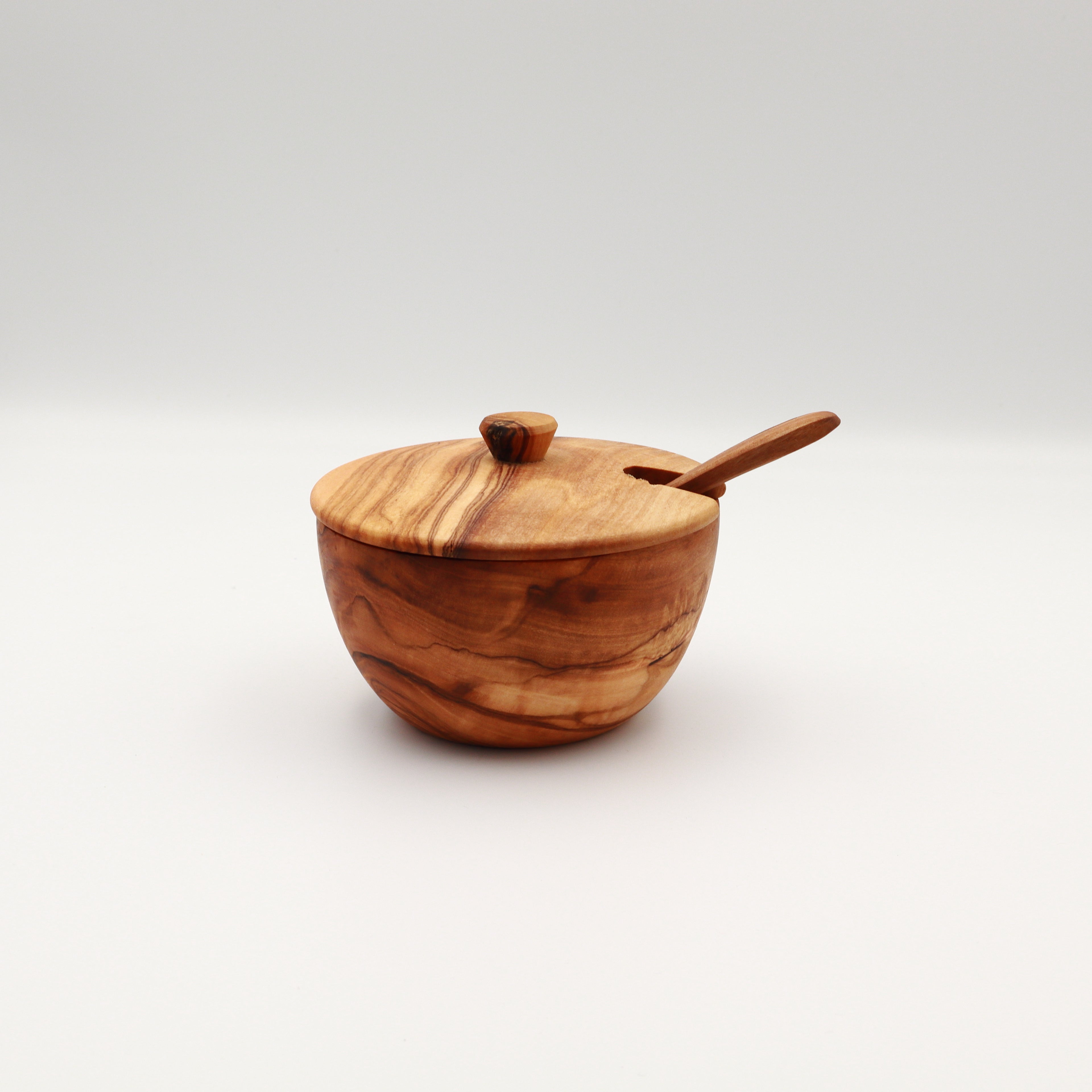 Single handcrafted Tunisian olive wood spice box with lid and serving spoon on a white background.