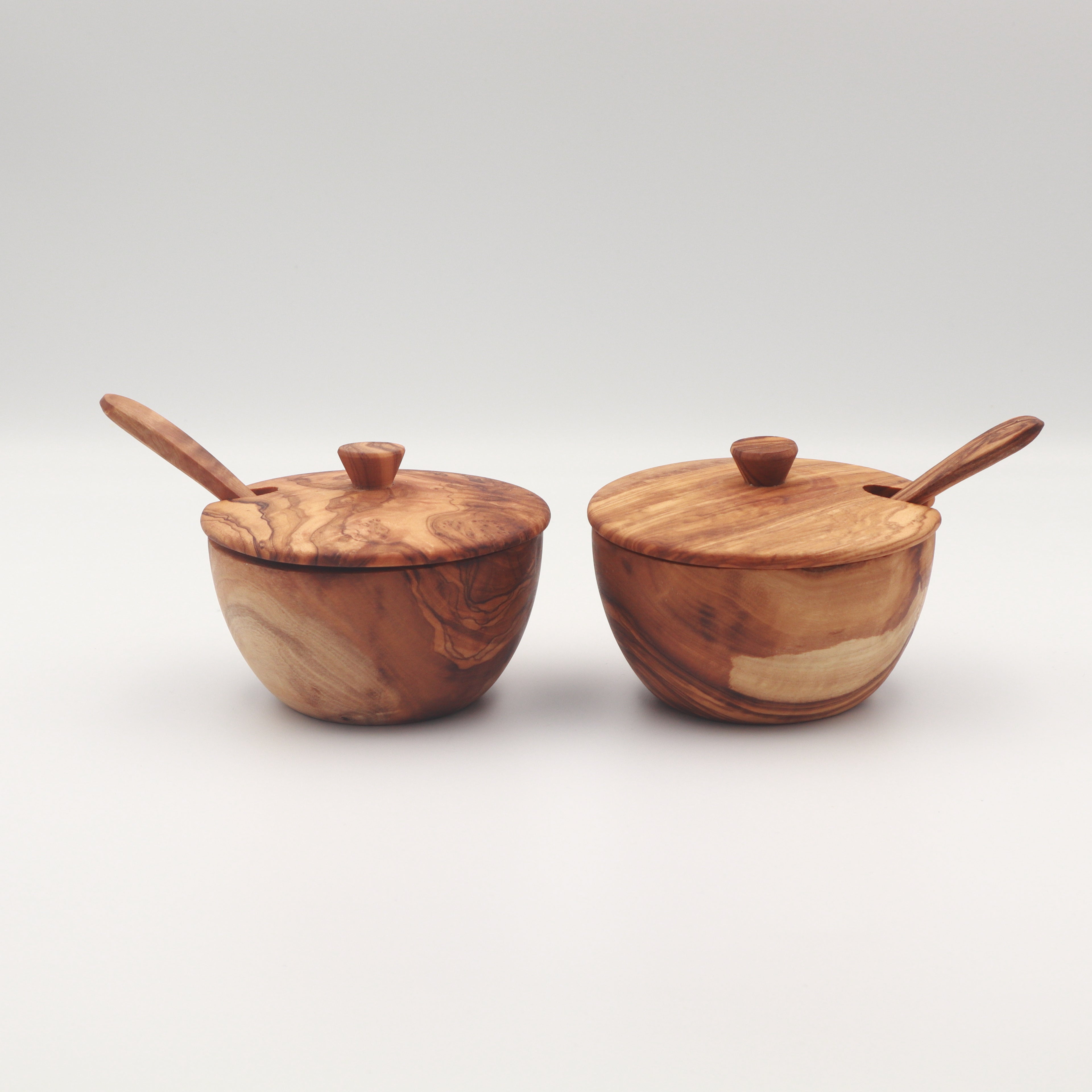 Pair of handcrafted Tunisian olive wood spice boxes with lids and serving spoons on a white background.