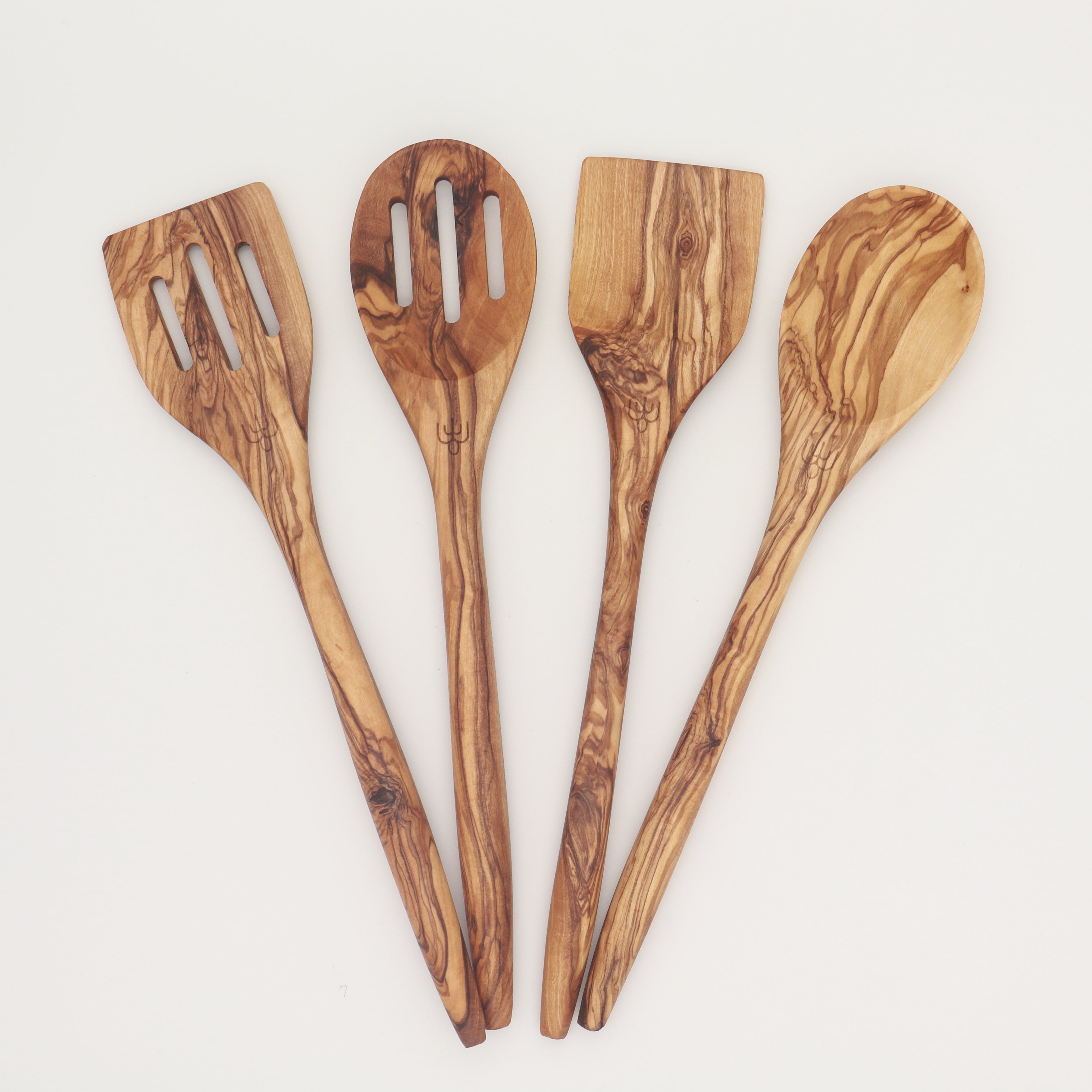 Handcrafted Tunisian olive wood four-piece utensil set with slotted spatula, slotted spoon, spatula, and mixing spoon arranged in a fan on a white background.