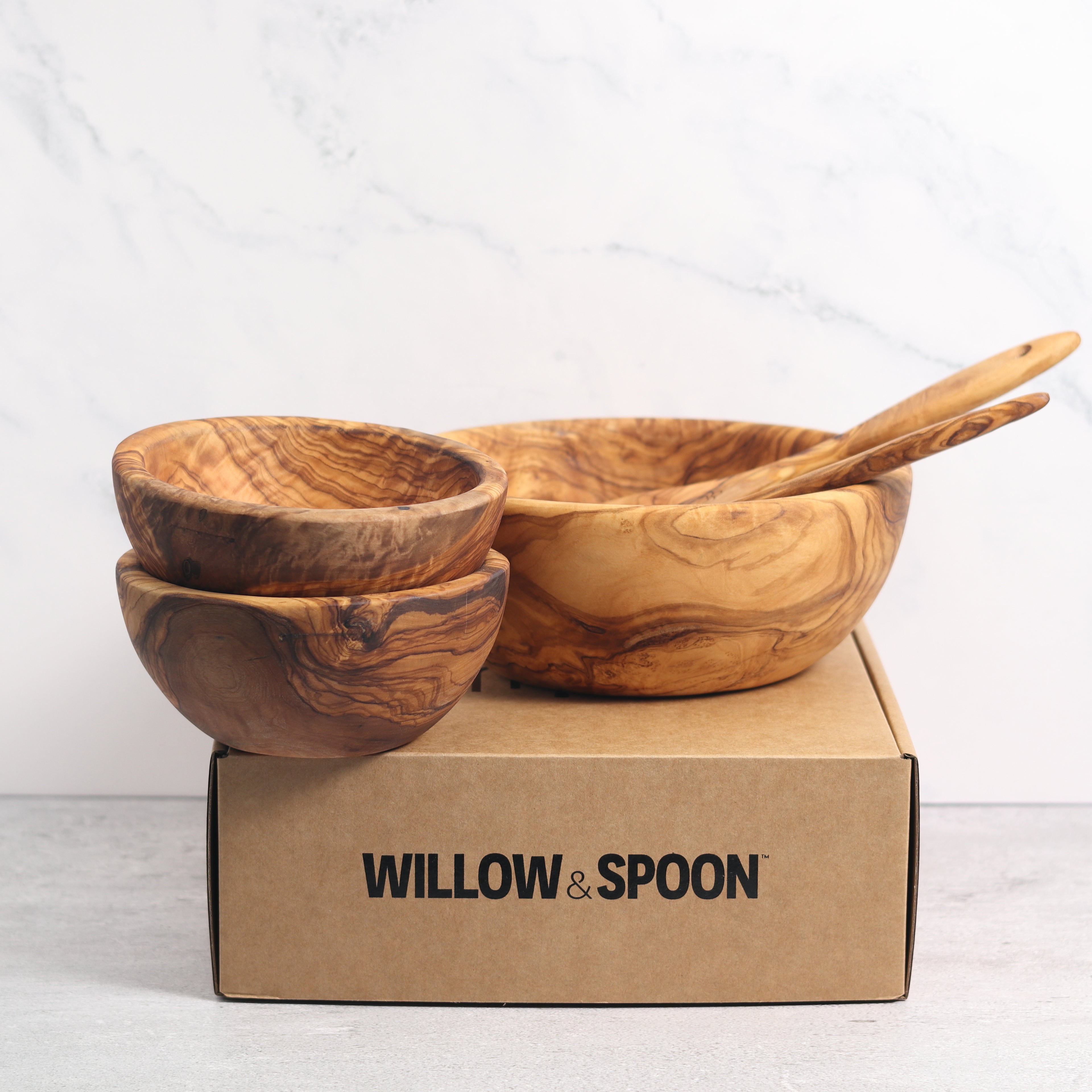 Olive wood salad bowl with servers and two small bowls displayed on a Willow & Spoon branded box against a marble background